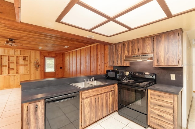 kitchen with dark countertops, under cabinet range hood, light tile patterned floors, black appliances, and a sink