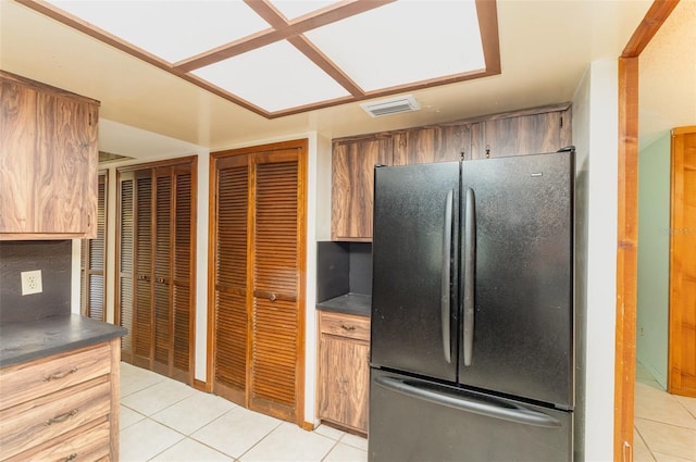 kitchen featuring light tile patterned floors, visible vents, dark countertops, and freestanding refrigerator