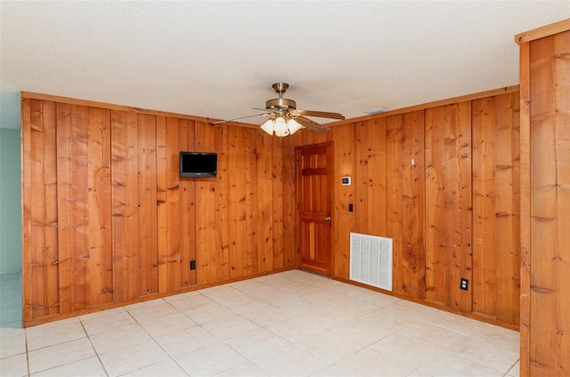 empty room with wooden walls, visible vents, and ceiling fan