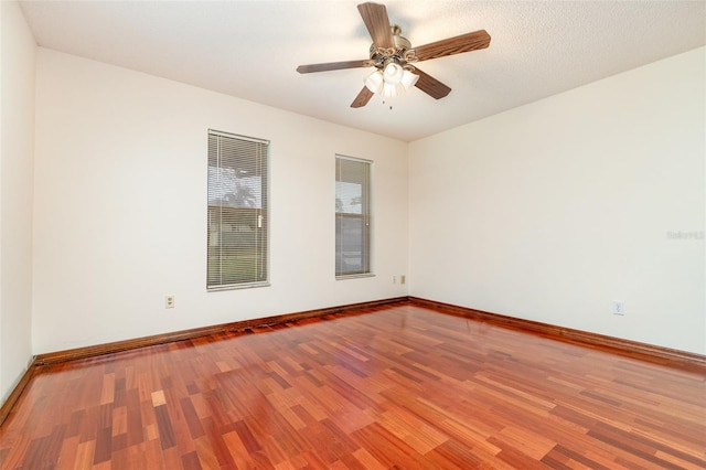 unfurnished room with baseboards, wood finished floors, and a ceiling fan