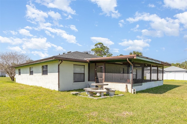 rear view of property featuring stucco siding, a lawn, fence, and a sunroom