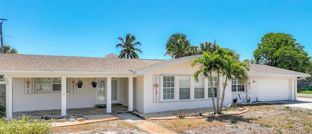 single story home with a garage, roof with shingles, and stucco siding