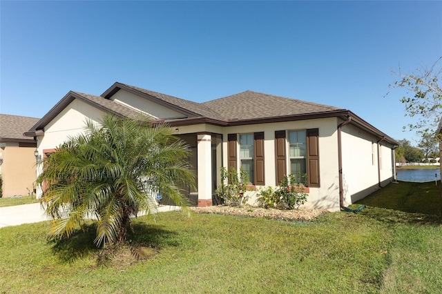 view of front of property with a front yard, an attached garage, roof with shingles, and stucco siding