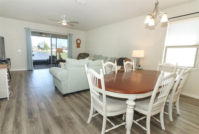 dining space featuring baseboards, wood finished floors, and ceiling fan with notable chandelier