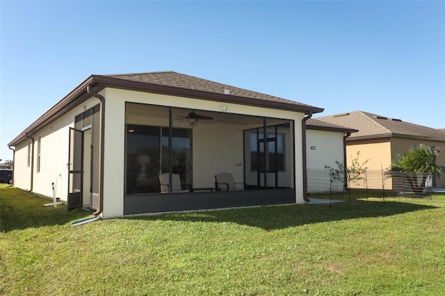 rear view of property with stucco siding, a lawn, a shingled roof, and a sunroom