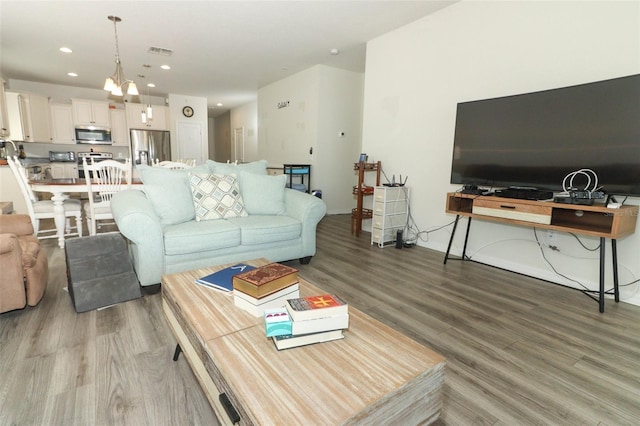 living room with recessed lighting, visible vents, light wood-style flooring, and baseboards