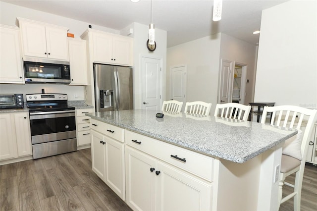 kitchen featuring a kitchen bar, appliances with stainless steel finishes, dark wood finished floors, and a center island