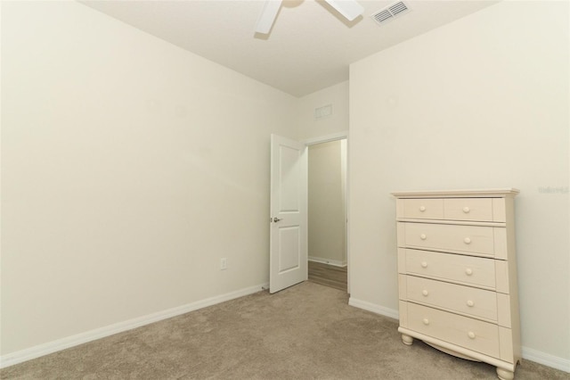 unfurnished bedroom featuring visible vents, baseboards, light colored carpet, and a ceiling fan