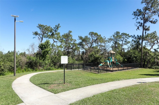 community play area featuring a yard and fence