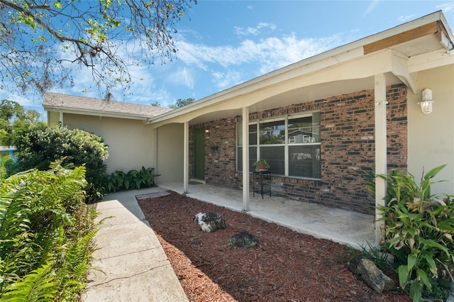 view of exterior entry featuring brick siding and stucco siding