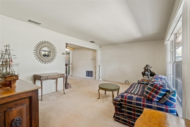 sitting room with visible vents, light carpet, and a textured ceiling