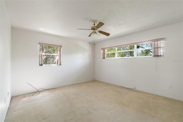 unfurnished room with light colored carpet, a textured ceiling, and a ceiling fan