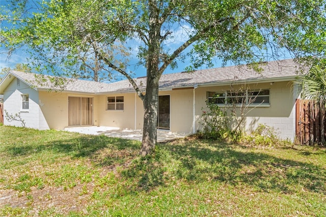 back of property featuring a patio, concrete block siding, a yard, and fence