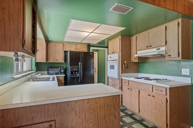 kitchen with visible vents, under cabinet range hood, a peninsula, white appliances, and a sink