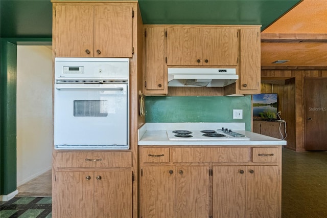 kitchen with under cabinet range hood, white appliances, and light countertops