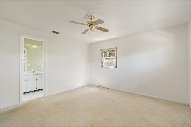 spare room featuring a ceiling fan, baseboards, visible vents, a sink, and light carpet