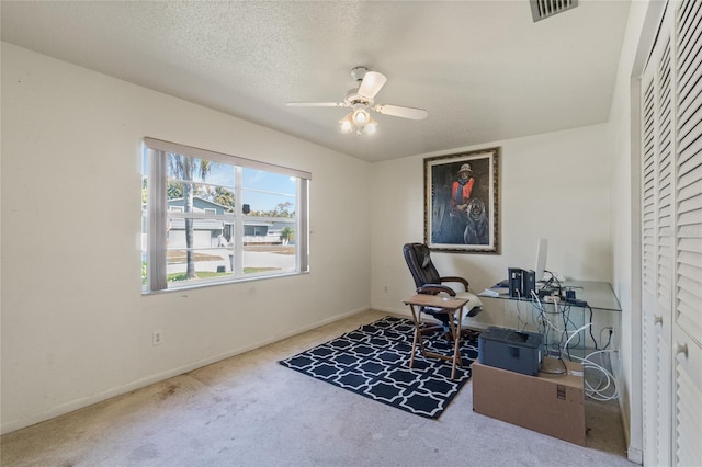 carpeted office space with visible vents, a textured ceiling, baseboards, and a ceiling fan