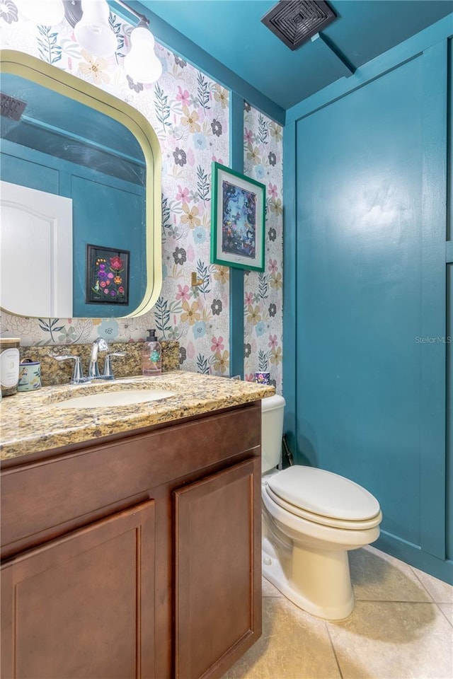 half bathroom with tile patterned flooring, visible vents, wallpapered walls, toilet, and vanity