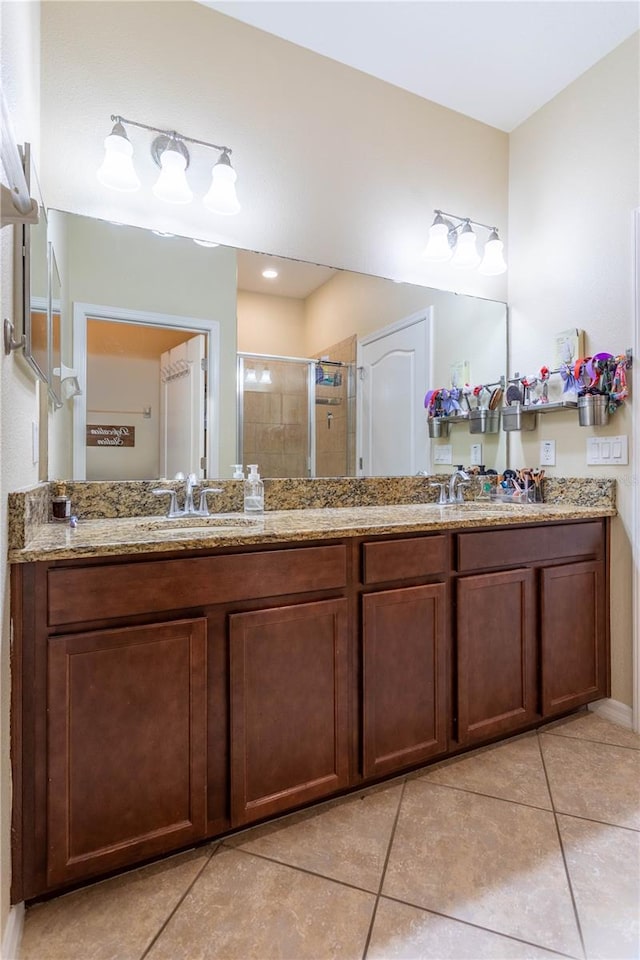 bathroom with tile patterned flooring, a stall shower, double vanity, and a sink