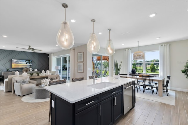 kitchen with a sink, dishwasher, wood tiled floor, and light countertops