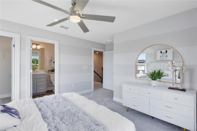 carpeted bedroom featuring visible vents, ceiling fan, ensuite bathroom, and baseboards