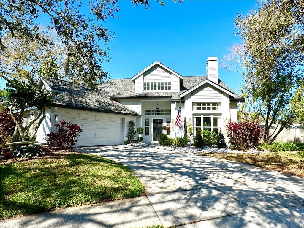 craftsman inspired home with stucco siding, driveway, a front yard, a garage, and a chimney