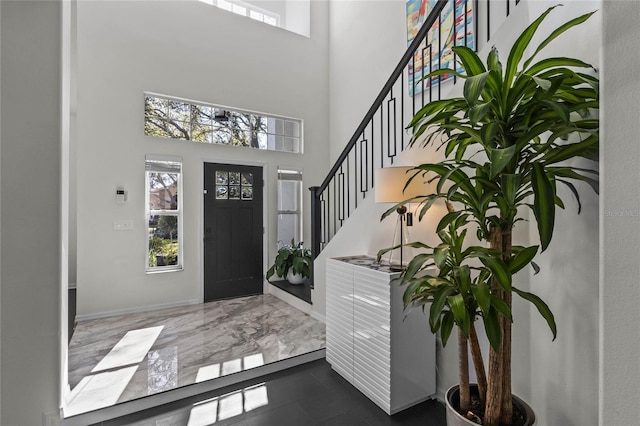 entryway with stairway, baseboards, a high ceiling, and marble finish floor