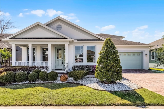 neoclassical / greek revival house with a front yard, driveway, a porch, an attached garage, and stucco siding