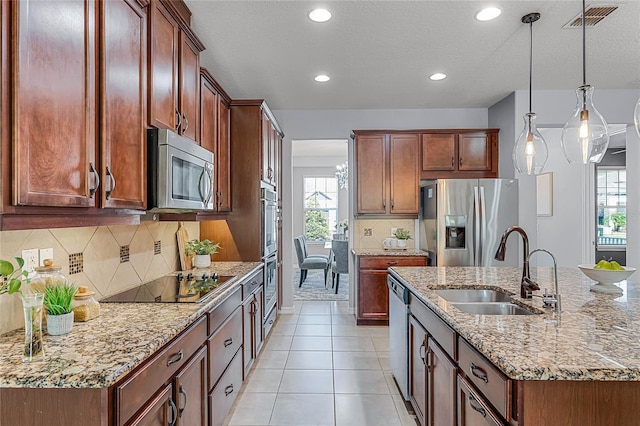 kitchen featuring visible vents, a sink, decorative light fixtures, tasteful backsplash, and stainless steel appliances