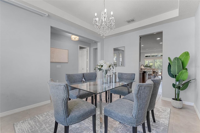 dining area with visible vents, a raised ceiling, a notable chandelier, and light tile patterned flooring