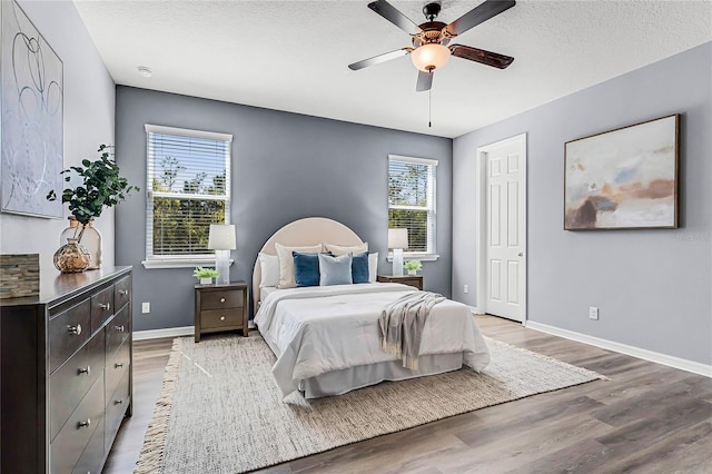 bedroom featuring light wood-type flooring, baseboards, a textured ceiling, and ceiling fan