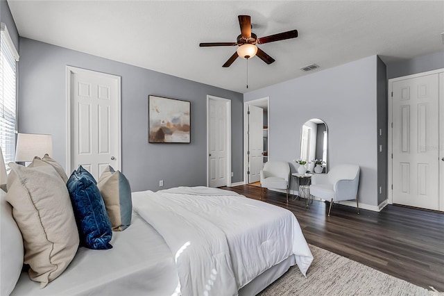 bedroom featuring wood finished floors, visible vents, baseboards, arched walkways, and ceiling fan