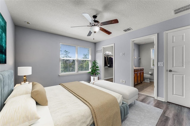 bedroom with visible vents, a textured ceiling, wood finished floors, and ensuite bathroom