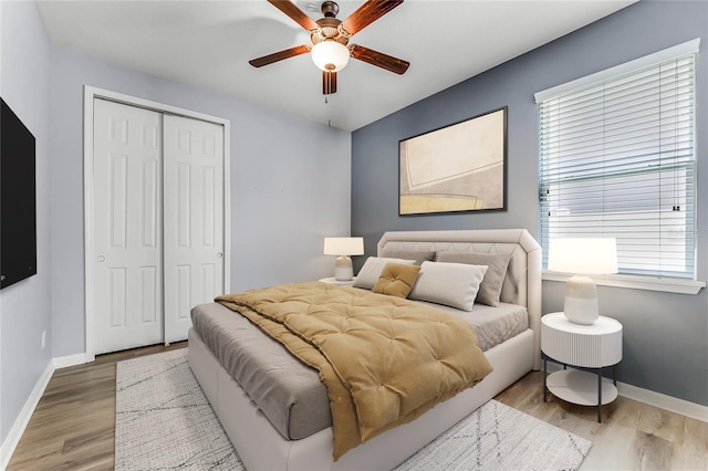 bedroom featuring a closet, ceiling fan, baseboards, and wood finished floors