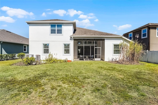 rear view of property featuring stucco siding, fence, a lawn, and a sunroom