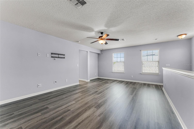 empty room with visible vents, a ceiling fan, a textured ceiling, baseboards, and dark wood-style flooring