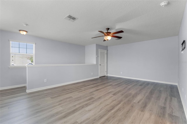 unfurnished room with visible vents, wood finished floors, baseboards, and ceiling fan