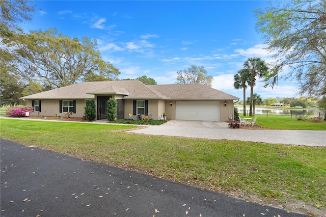 ranch-style home with a front lawn, a water view, stucco siding, decorative driveway, and a garage