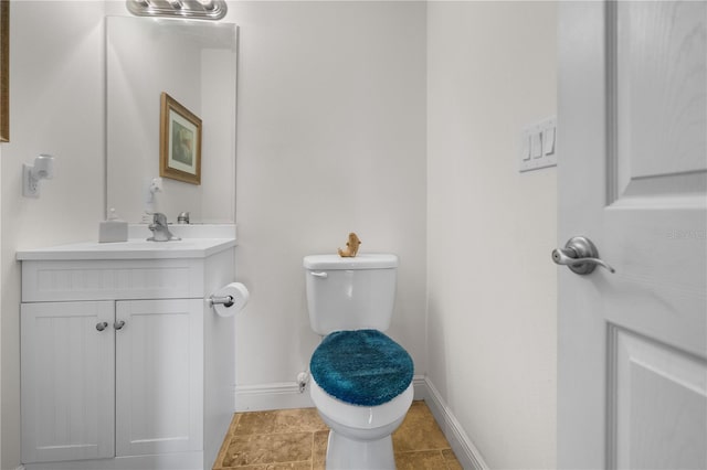 bathroom with toilet, vanity, and baseboards