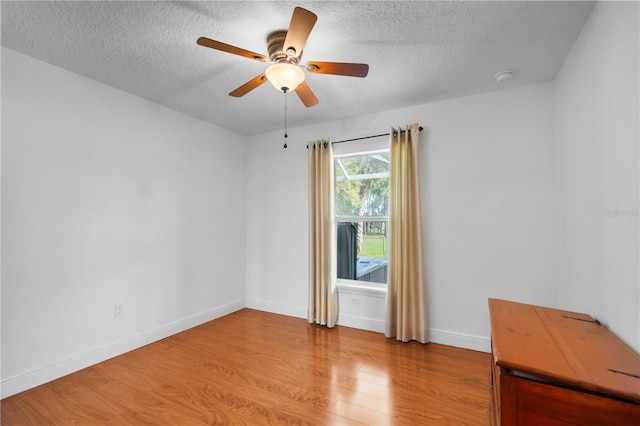 unfurnished room featuring baseboards, light wood-style floors, a ceiling fan, and a textured ceiling