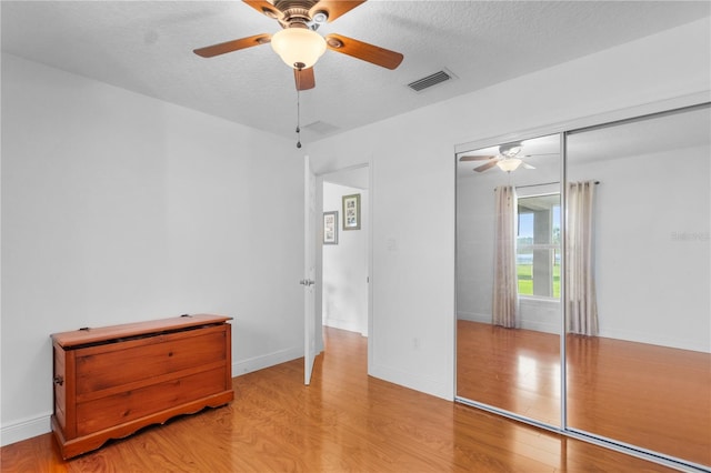 unfurnished bedroom featuring baseboards, visible vents, a textured ceiling, and light wood-style floors