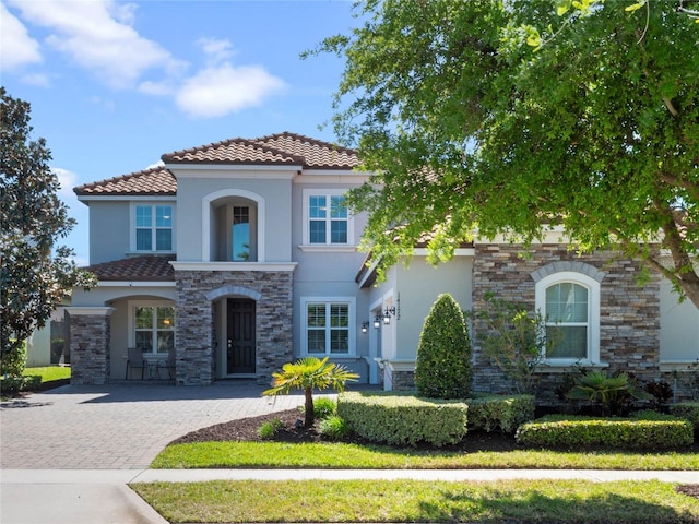 mediterranean / spanish house with a tiled roof, stucco siding, and driveway