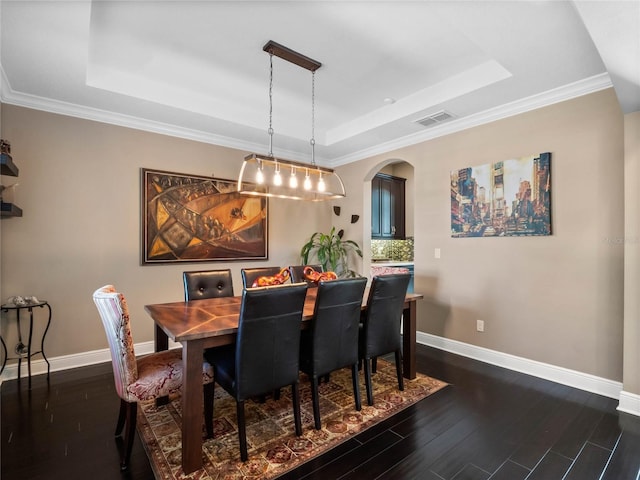 dining space featuring dark wood-style floors, visible vents, baseboards, arched walkways, and a raised ceiling