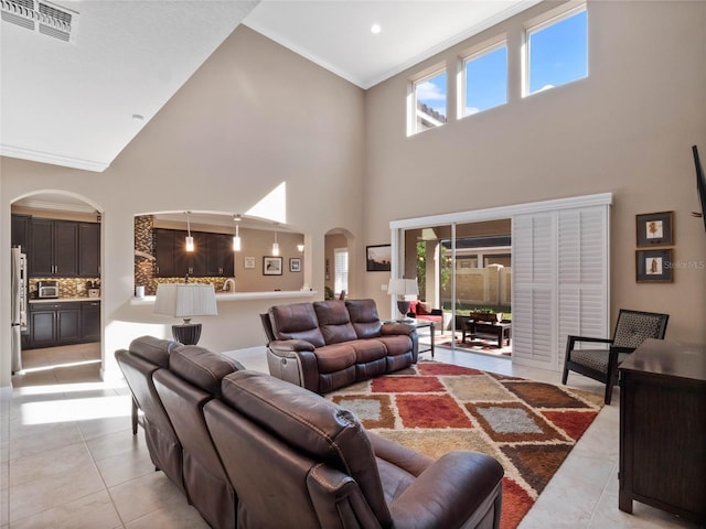 living room featuring light tile patterned floors, visible vents, arched walkways, and a wealth of natural light