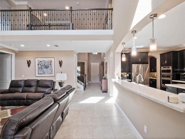 living area featuring arched walkways, a towering ceiling, and ornamental molding