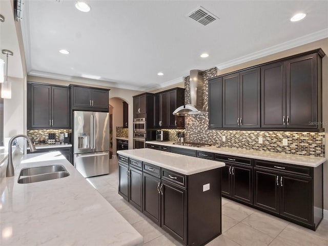 kitchen featuring visible vents, a sink, arched walkways, appliances with stainless steel finishes, and wall chimney range hood