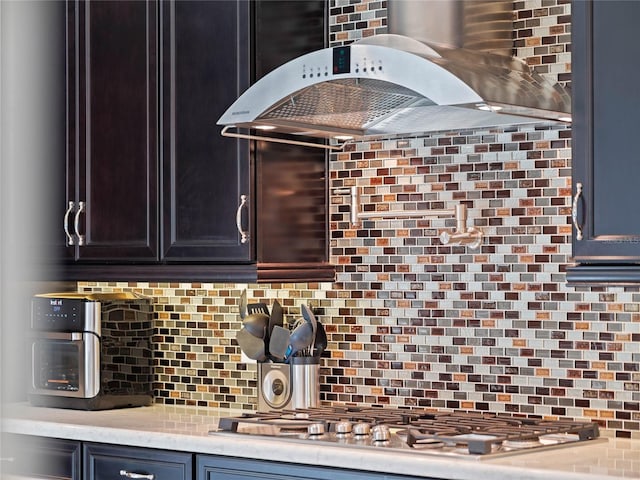 kitchen featuring ventilation hood, backsplash, and stainless steel gas stovetop