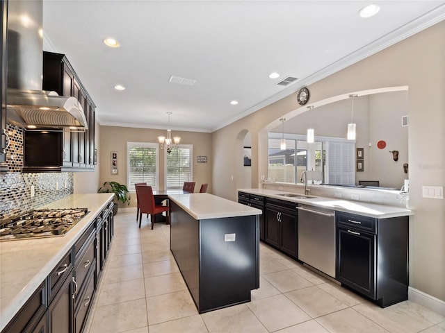 kitchen featuring visible vents, a kitchen island, a sink, appliances with stainless steel finishes, and wall chimney range hood