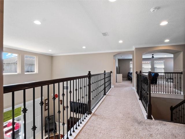 hall featuring crown molding, carpet flooring, arched walkways, and visible vents