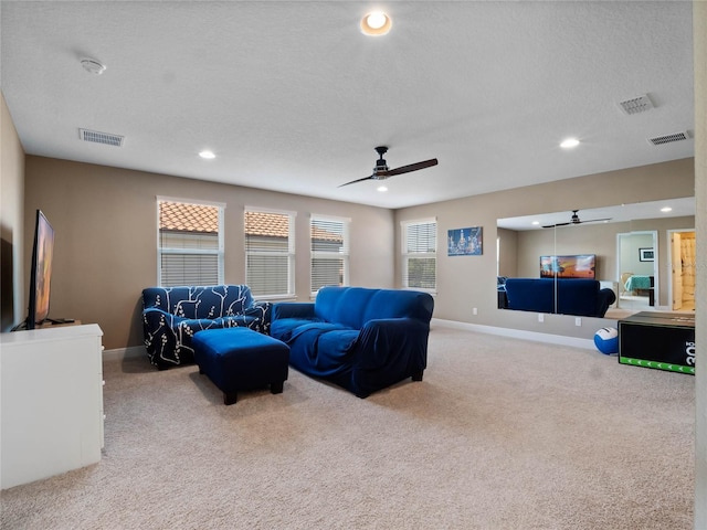 living room with visible vents, carpet, ceiling fan, and a textured ceiling